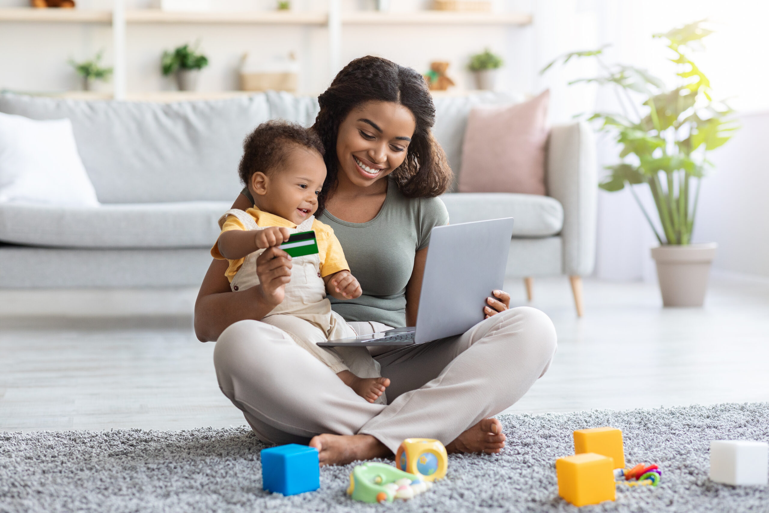 Young Black Mother With Infant Baby Using Laptop And Credit Card For Online Shopping At Home, African American Mom Holding Cute Toddler Child On Lap And Enjoying Purchasing From Internet, Copy Space